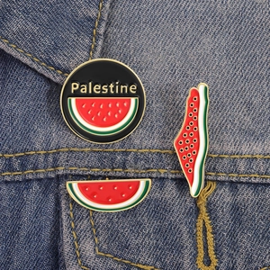 Dettaglio delle spille in smalto con anguria a tema Palestina su sfondo denim blu