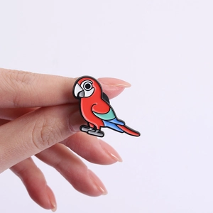 Close-up of a colorful parrot enamel brooch featuring vibrant red, blue, and green colors