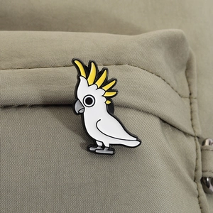 Close-up van een schattige kaketoe emaille speld op een beige rugzak van textielstof