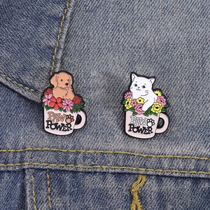 Cute enamel paw power brooches with cat and dog in flower cups on denim background