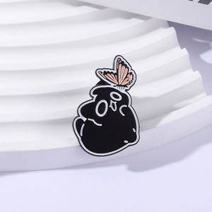 Creative dark cat enamel pin with a pink butterfly accent on a white waved stand