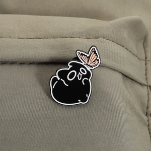 Détail d'un pin's en émail chat fantôme noir avec papillon rose sur sac vert olive
