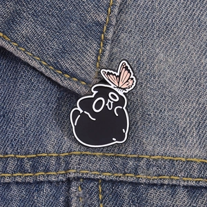 Gothic black coal monster enamel pin with pink butterfly on denim jacket fabric