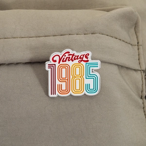 Detailed macro view of Vintage 1985 enamel pin attached to khaki canvas material