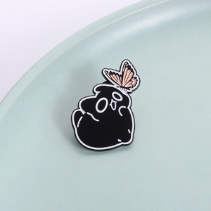 Broche chat noir émaillé avec papillon rose sur un support en céramique minimaliste