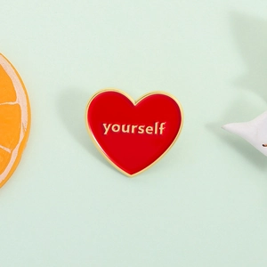 Broche cœur émaillée rouge avec lettrage yourself doré sur un fond vert clair