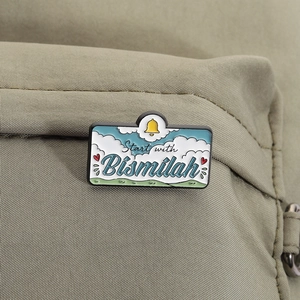 Détail du pin's émaillé Bismillah avec motif ciel fixé sur un sac en toile olive