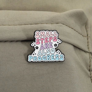Détail du badge émaillé sur toile avec texte Small Steps Are Also Progress