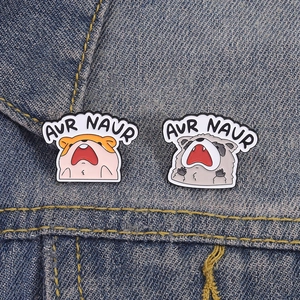 Funny animal enamel pins with screaming hamster and raccoon on denim fabric background
