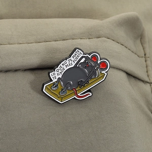 Detail of enamel mouse pin with Spanish text LO QUE NO TE MATA TE HACE MÁS FUERTE