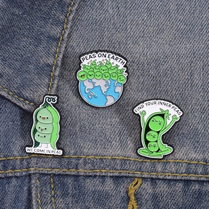 Three cute pea-themed enamel pins with funny puns attached to a blue denim jacket pocket