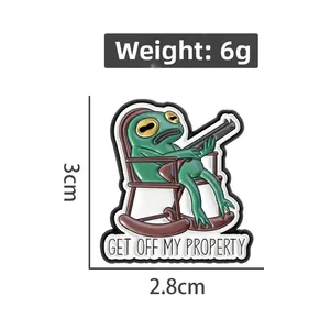 Detailansicht der Frosch-Anstecknadel mit Pistole und GET OFF MY PROPERTY Schriftzug