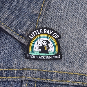 Gothic Grim Reaper enamel pin with rainbow on denim background, Halloween accessory badge
