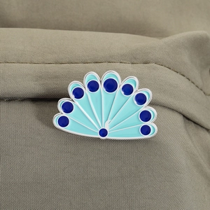 Gros plan sur la broche émaillée en plume de paon épinglée sur un tissu kaki texturé