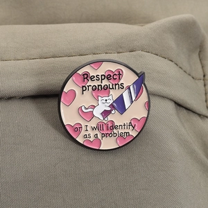 Détail du badge chat en émail avec texte Respect Pronouns sur tissu en toile beige