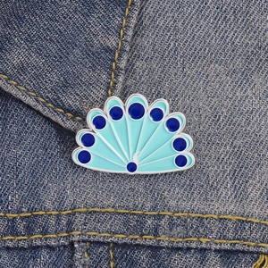 Peacock enamel pin with blue feathers shown on denim jacket for clothing decoration