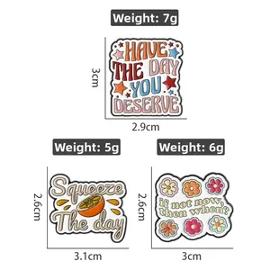 Enamel badges detail showing star and fruit motifs with motivational quotes and dimensions