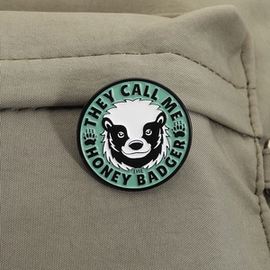 Gros plan d'un pin's en émail de blaireau à miel avec slogan sur tissu en toile