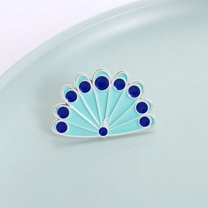 Exquisite peacock feather brooch with blue enamel inlay on a decorative ceramic tray