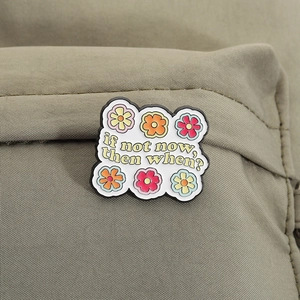 Detailansicht der wolkenförmigen Blumenbrosche mit Spruch auf grünem Stoff