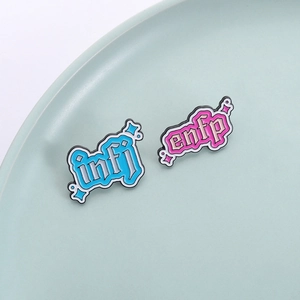 Blue INFJ and pink ENFP enamel pins with gothic lettering on a ceramic plate