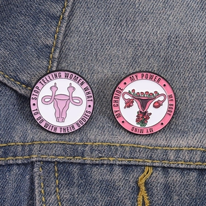 Detail of feminist enamel pins with quote on denim fabric background