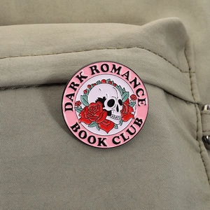 Detail of Gothic enamel pin featuring skull and red roses for Dark Romance Book Club