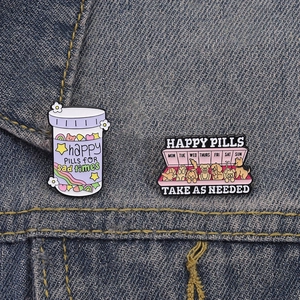 Detail of happy pills enamel pins featuring cartoon puppies and rainbow on denim jacket