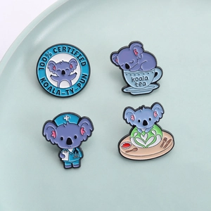 Cute set of 4 blue enamel koala pins with punny slogans in a ceramic dish