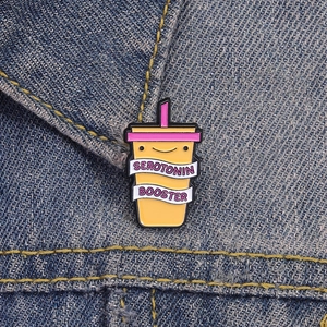 Emaille-Pin Serotonin Booster an einer blauen Jeansjacke als modisches Detail