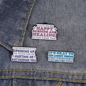 Tre spille in smalto per la salute mentale con frasi motivazionali su denim