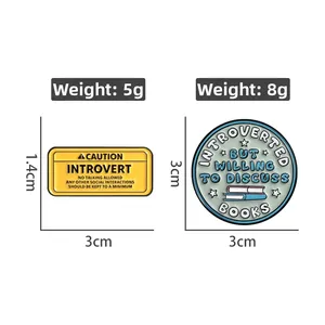 Detail view of two metal introvert badges with size and weight measurements in centimeters