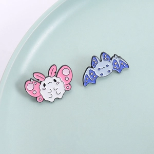 Cute cartoon bat and butterfly enamel pins on a light blue ceramic plate decoration