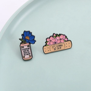 Emaille-Anstecknadel-Set mit positiven Zitaten auf einem pastellgrünen Keramikteller