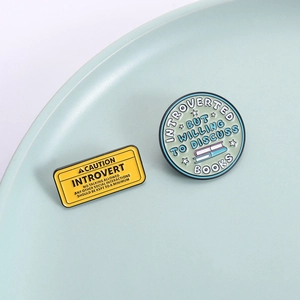 Introvert-themed metal enamel pins featuring humorous quotes and book illustrations