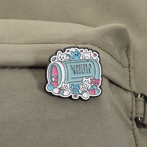 Detail of cute cat enamel pin with serotonin booster bottle on olive green fabric