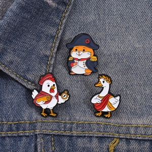 Detailed view of hamster, rooster, and goose enamel pins on blue denim fabric