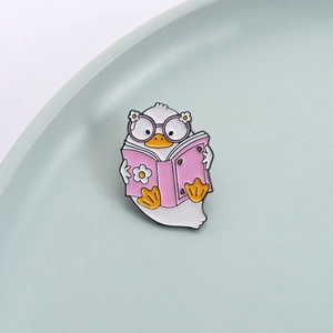 Creative cartoon duck enamel pin wearing purple glasses reading a pink book for backpack