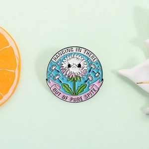 Cartoon dandelion enamel pin badge with pink ribbon and Hanging in There slogan