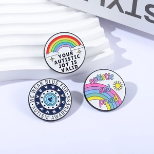 Tre spille in smalto per la sensibilizzazione all'autismo con design arcobaleno su base bianca