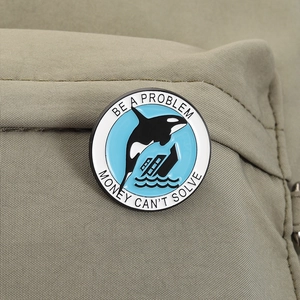 Orca whale enamel pin with slogan on khaki canvas backpack showing detailed wear effect