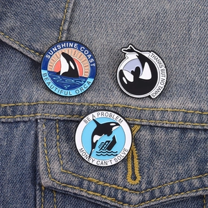 Orca whale enamel pins set on denim background featuring sunset and oceanic designs