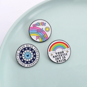 Enamel autism awareness pins with rainbow designs on a ceramic tray for social support