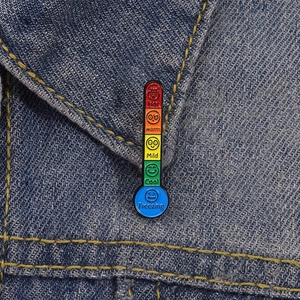 Detail of creative enamel thermometer brooch with color gradient on denim jacket collar