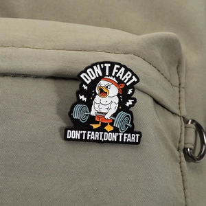 Detail der lustigen Muskelente-Emaille-Anstecknadel mit Spruch auf einer grünen Tasche