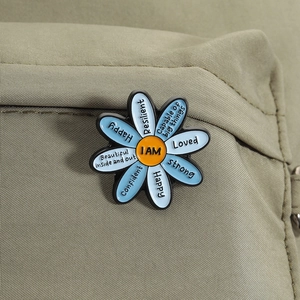 Macro shot of daisy enamel pin with positive affirmations on a canvas bag