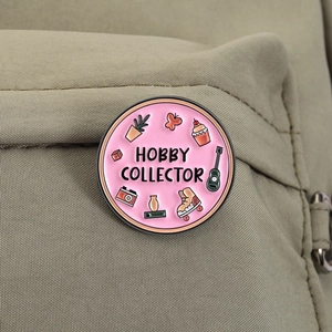 Detailed close-up of a pink Hobby Collector enamel pin on a green canvas backpack fabric