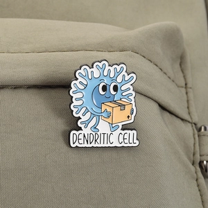 Detail of a cartoon dendritic cell enamel pin attached to a khaki canvas bag