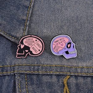 Detailed macro of pink skull enamel pins on denim, showing snacks and coffee text detail