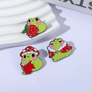 Three creative crown and mushroom frog alloy enamel pins set on a white tiered display